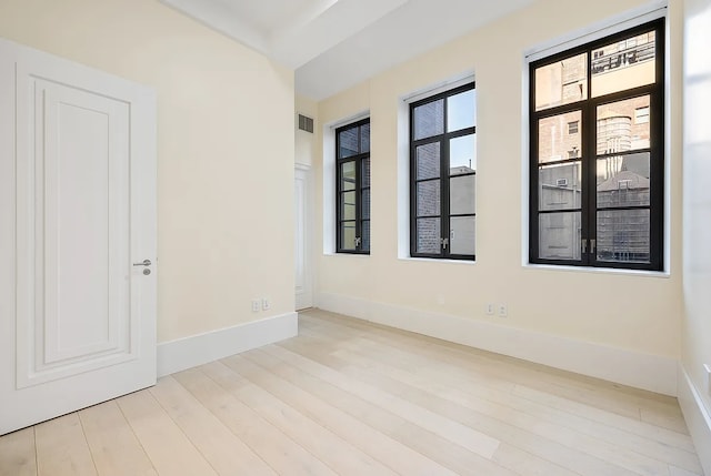 spare room with baseboards, visible vents, and wood finished floors
