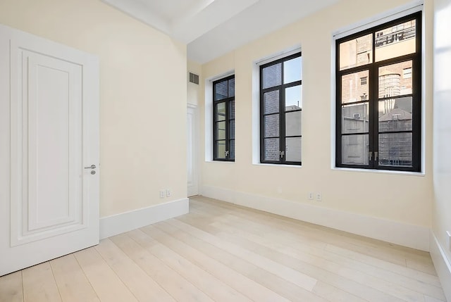 spare room with baseboards, visible vents, and wood finished floors