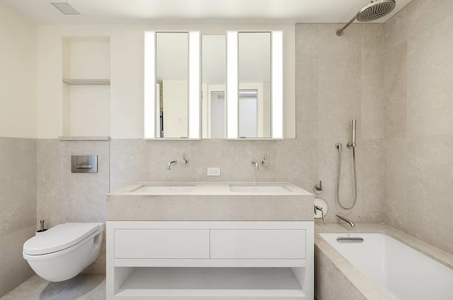 bathroom featuring a sink, visible vents, tiled shower / bath, toilet, and tile walls