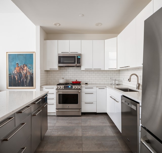 kitchen featuring light stone countertops, appliances with stainless steel finishes, backsplash, and a sink