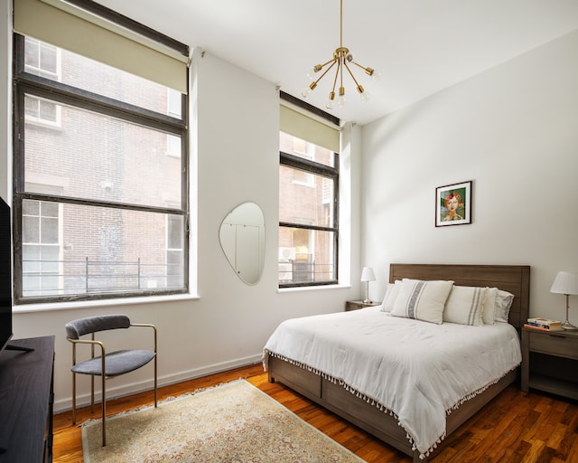 bedroom with multiple windows, wood finished floors, and a notable chandelier