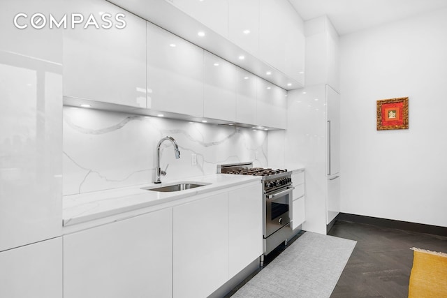 kitchen with backsplash, white cabinetry, a sink, modern cabinets, and high end stove