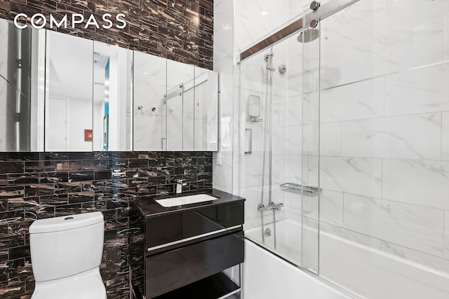 bathroom featuring tile walls, tasteful backsplash, toilet, enclosed tub / shower combo, and vanity