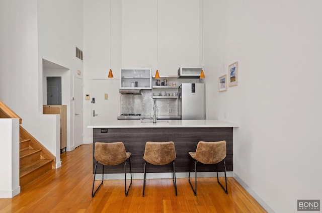 kitchen with visible vents, freestanding refrigerator, a peninsula, open shelves, and backsplash