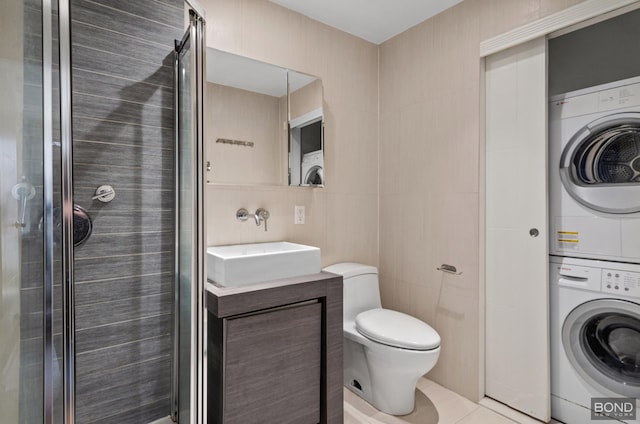 full bathroom featuring stacked washer / dryer, toilet, tile patterned floors, vanity, and a shower stall