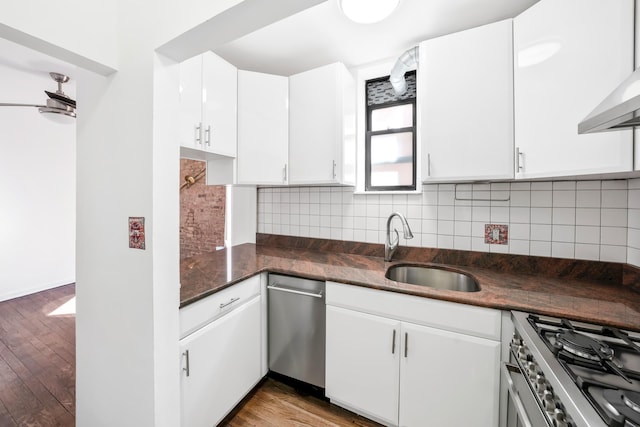 kitchen with a sink, backsplash, wood finished floors, and stainless steel gas range