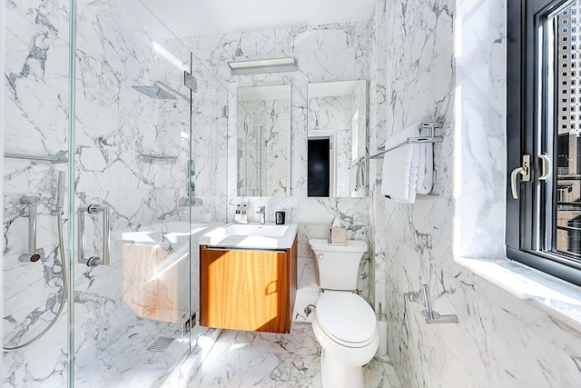 bathroom featuring marble finish floor, a marble finish shower, toilet, vanity, and stone wall