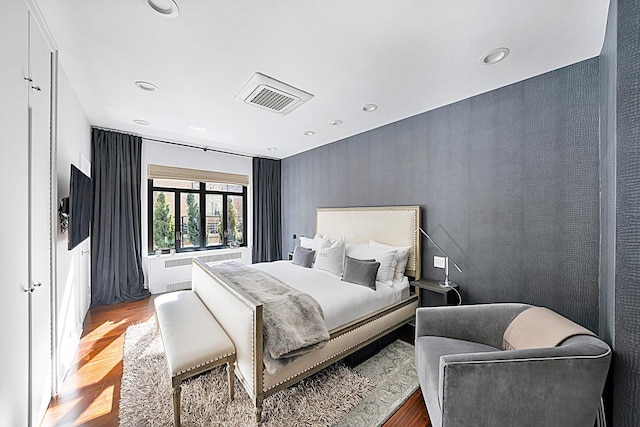 bedroom featuring radiator heating unit, visible vents, wood finished floors, and recessed lighting