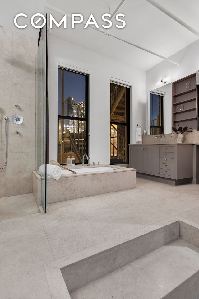 bathroom featuring tiled shower, a garden tub, and vanity