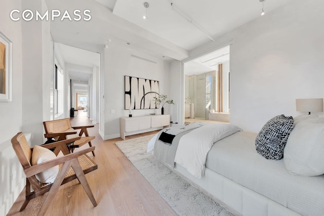 bedroom featuring light wood-type flooring, baseboards, and connected bathroom