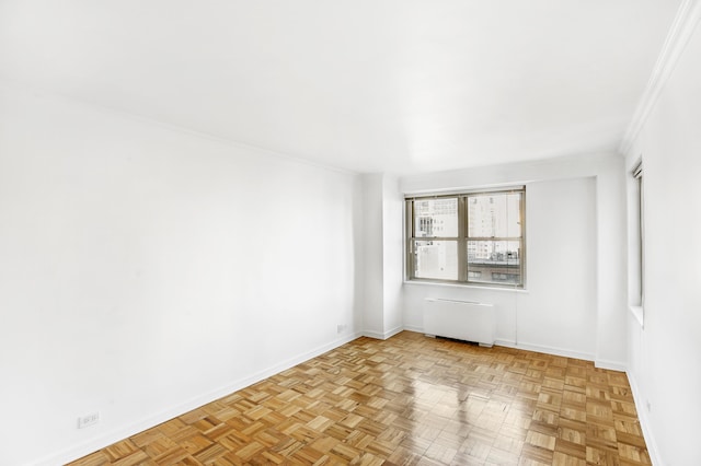 spare room featuring baseboards, radiator heating unit, and crown molding