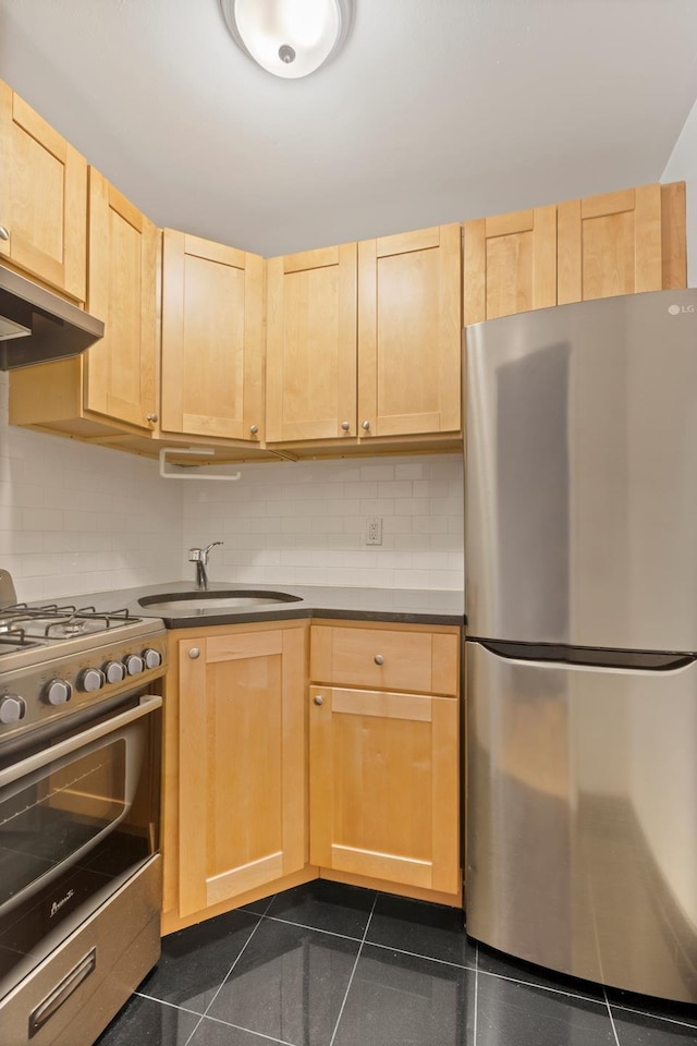 kitchen with a sink, decorative backsplash, light brown cabinetry, under cabinet range hood, and appliances with stainless steel finishes