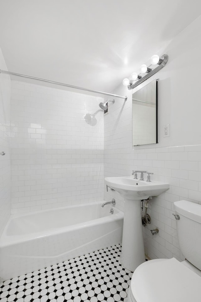 full bath featuring shower / bath combination, toilet, and tile walls