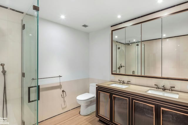 full bath with a sink, wood finished floors, toilet, and a shower stall