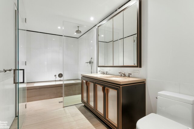 bathroom featuring a sink, a shower stall, toilet, and double vanity