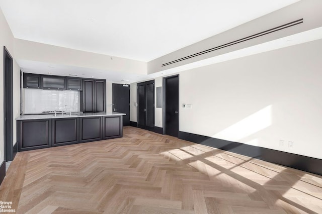 kitchen with tasteful backsplash, light countertops, a peninsula, and baseboards