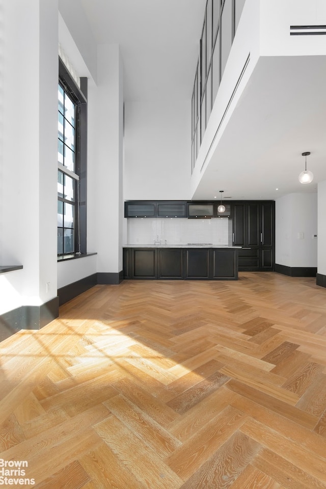 unfurnished living room featuring baseboards and a towering ceiling