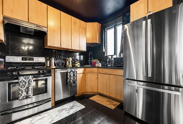 kitchen with stainless steel appliances, dark tile patterned floors, exhaust hood, backsplash, and dark countertops