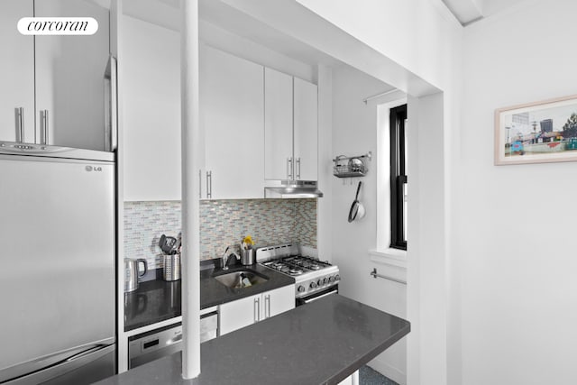 kitchen featuring stainless steel refrigerator, under cabinet range hood, a sink, range with gas stovetop, and white cabinets