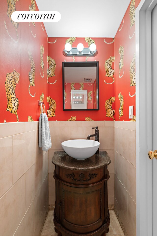 bathroom with wainscoting, tile walls, and vanity