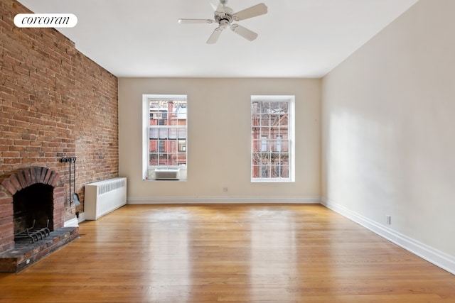 unfurnished living room featuring a brick fireplace, baseboards, ceiling fan, radiator heating unit, and light wood finished floors