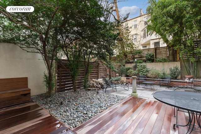 wooden deck with a fenced backyard and a patio area
