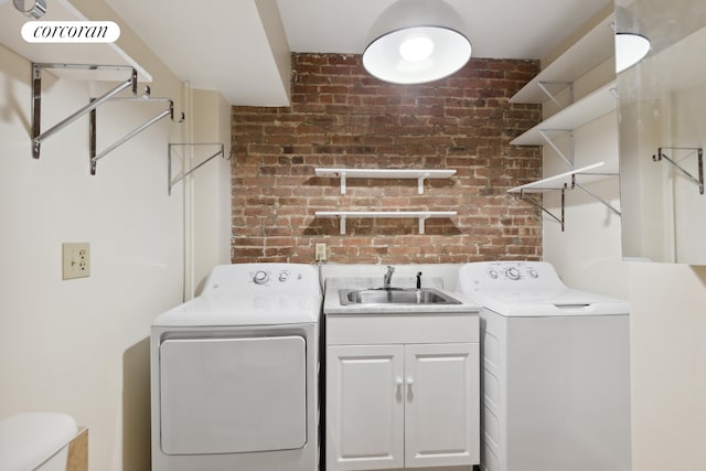 laundry room featuring laundry area, washing machine and dryer, brick wall, and a sink