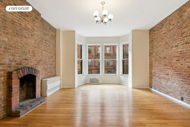 unfurnished living room featuring baseboards, an inviting chandelier, light wood finished floors, and a fireplace