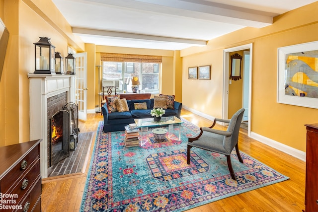 living room featuring beam ceiling, wood finished floors, a fireplace, and baseboards