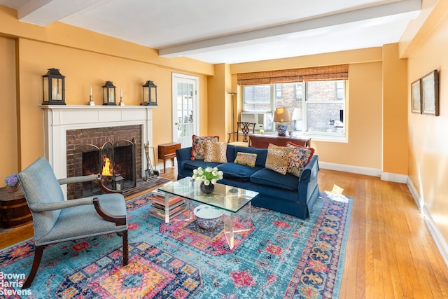 living area with cooling unit, baseboards, beamed ceiling, wood-type flooring, and a brick fireplace