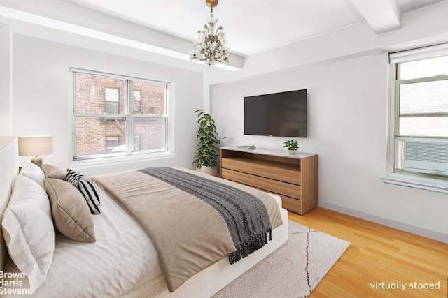 414 E 52nd St Unit 10E, New York City, NY 10022 - bedroom with a chandelier, light wood-style flooring, and baseboards