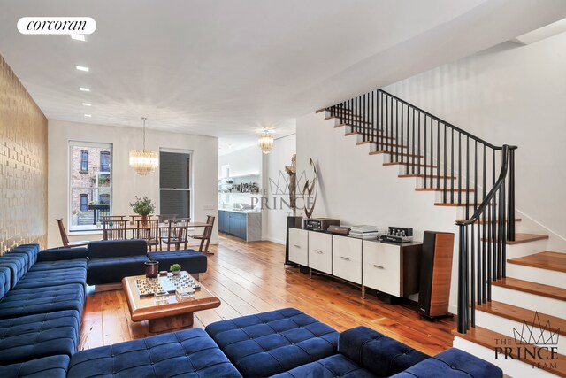 living room featuring visible vents, hardwood / wood-style flooring, recessed lighting, stairway, and a chandelier