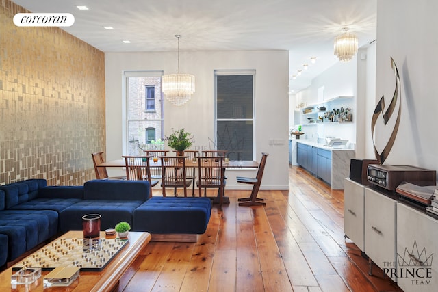 living room featuring visible vents, hardwood / wood-style flooring, recessed lighting, an inviting chandelier, and brick wall