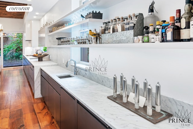 bar with wood finished floors and a sink