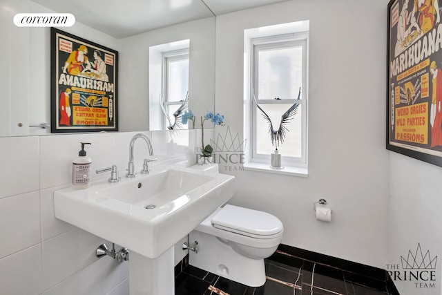 half bath with decorative backsplash, tile patterned floors, toilet, and baseboards