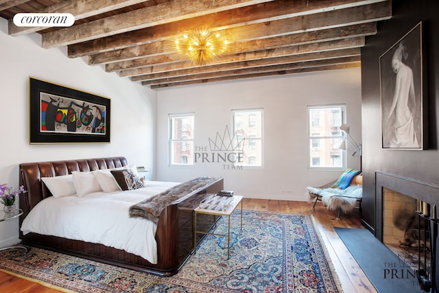 bedroom featuring beamed ceiling, multiple windows, visible vents, and hardwood / wood-style flooring