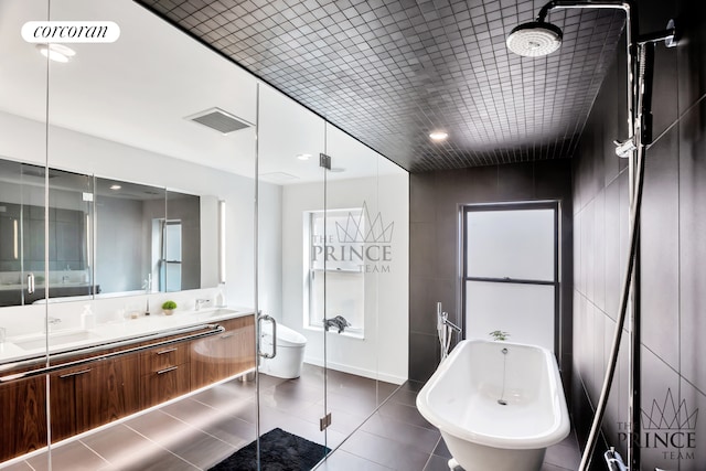 bathroom featuring double vanity, a freestanding tub, visible vents, and a sink