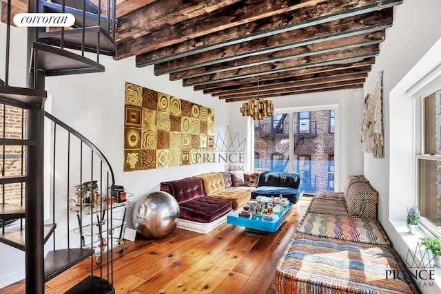 living area with plenty of natural light, beamed ceiling, stairs, and hardwood / wood-style flooring