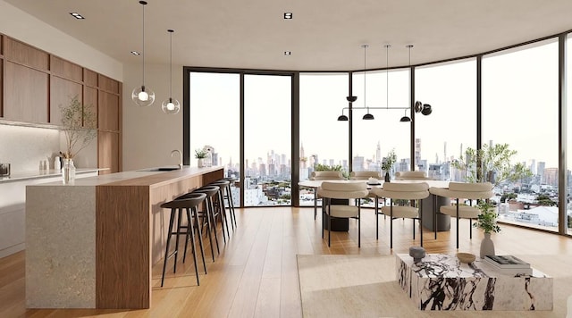 dining area with light wood finished floors, a wall of windows, and a city view