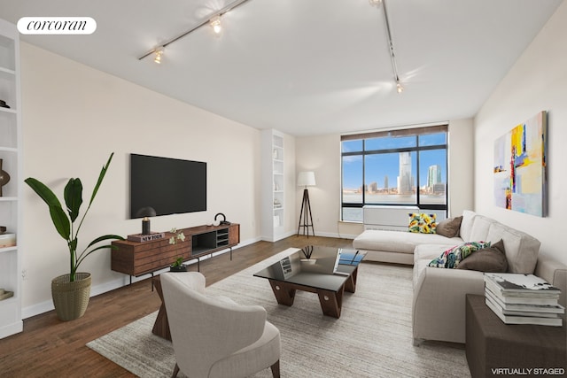 living room with built in shelves, wood finished floors, visible vents, baseboards, and track lighting