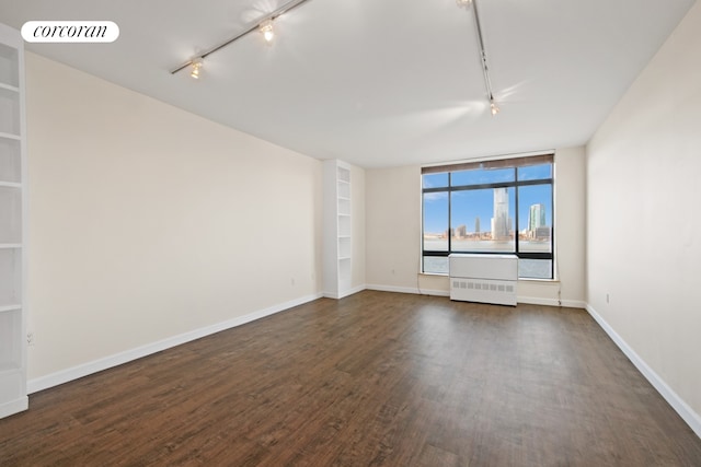 spare room with dark wood finished floors, built in features, radiator, and visible vents