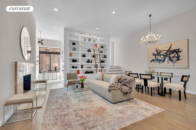 living room with visible vents, baseboards, a chandelier, stairway, and wood finished floors