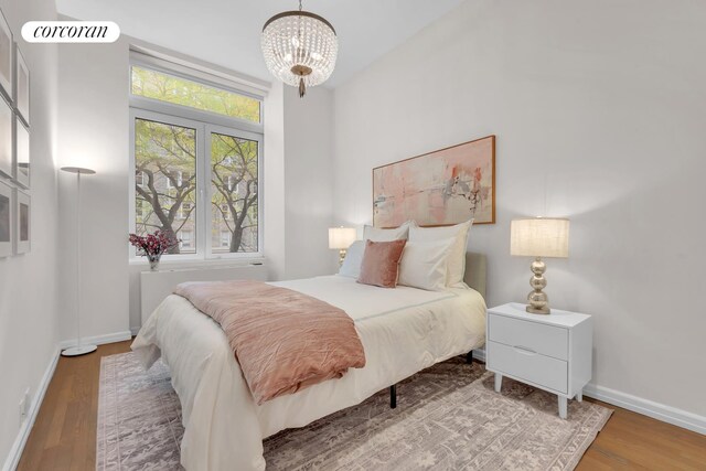 30 W 86th St Unit 2B, New York City, NY 10024 - bedroom featuring wood finished floors, a chandelier, and baseboards