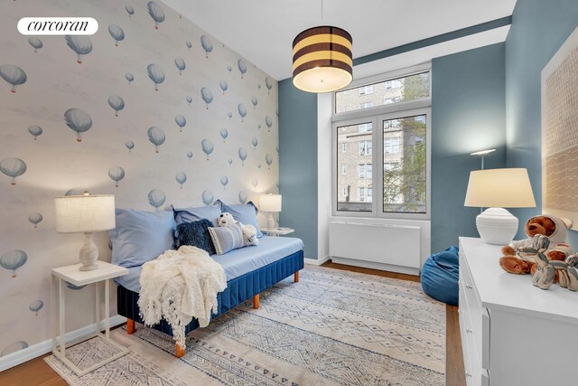 30 W 86th St Unit 2B, New York City, NY 10024 - bedroom featuring an accent wall, wood finished floors, baseboards, and wallpapered walls