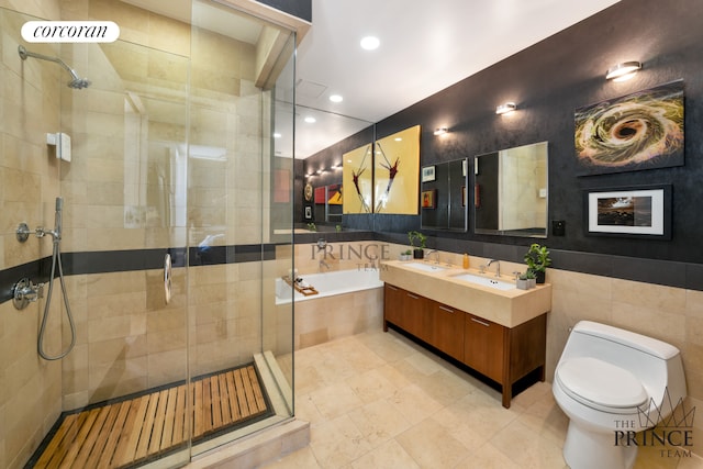bathroom featuring tile walls, a stall shower, toilet, double vanity, and a garden tub