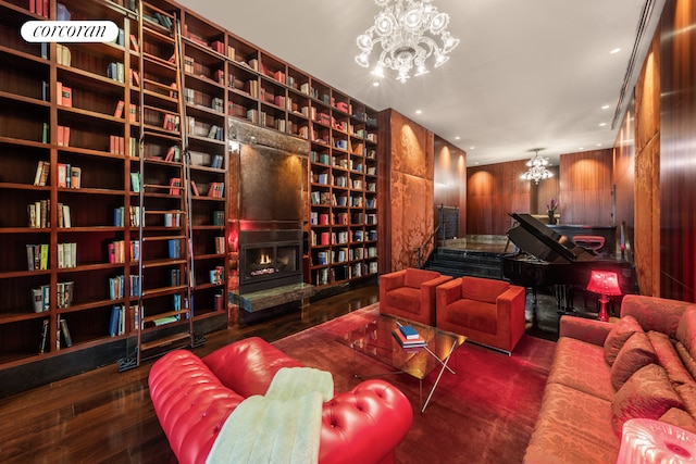 interior space featuring wood walls, a lit fireplace, recessed lighting, an inviting chandelier, and wood-type flooring