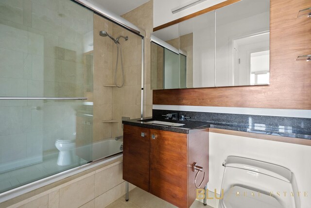 bathroom with tiled shower / bath combo, vanity, and toilet