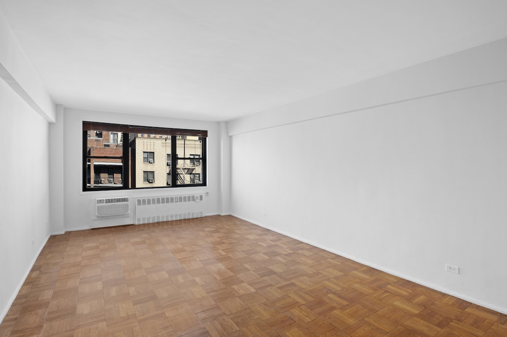 unfurnished room featuring radiator heating unit and a wall mounted AC