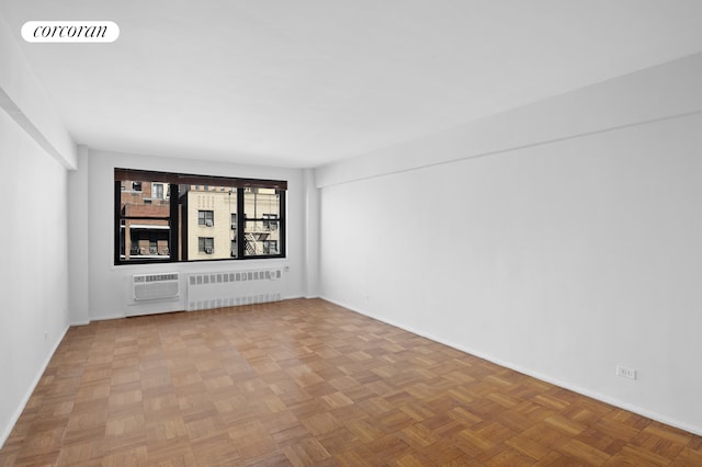 spare room with baseboards, visible vents, radiator heating unit, and a wall mounted AC