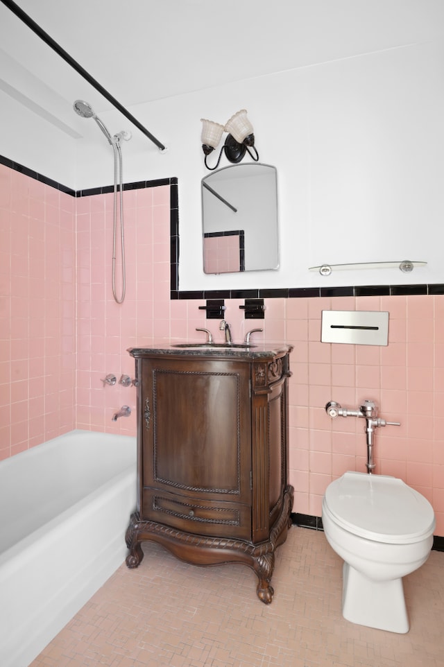 full bathroom featuring tile walls, toilet, washtub / shower combination, wainscoting, and vanity